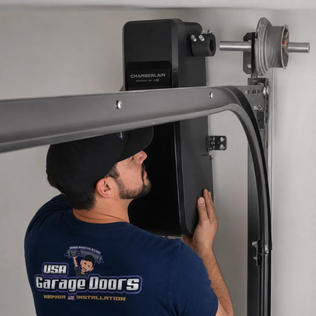 USA Garage Doors technician installing a wall-mounted Chamberlain jackshaft opener on a residential torsion shaft